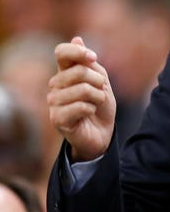 A photo of a hand doing a pinchy, half-committed 'thumbs up' gesture common amongst political speakers